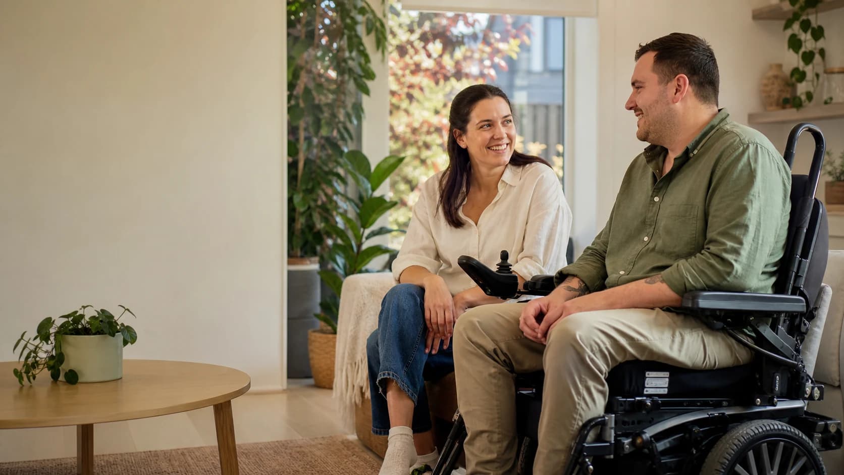 A disability support worker having a relaxed conversation with an adult participant at home