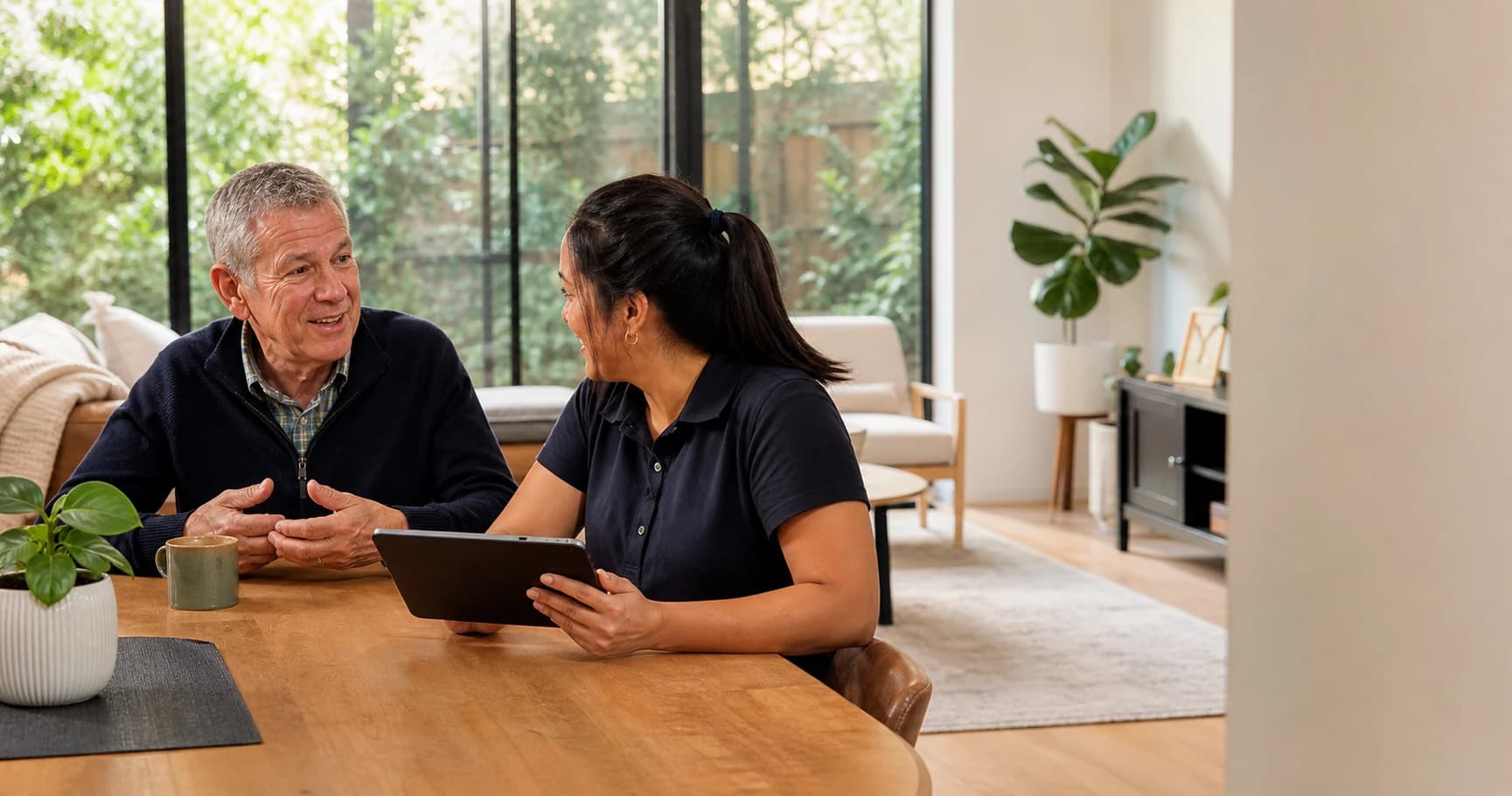 A support worker preparing a participant update on a tablet during a natural conversation